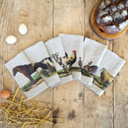 Set of animal-themed napkins on a wooden surface with bread and eggs.