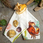 Napkin with sea-themed design featuring shells and a crab on a concrete surface.