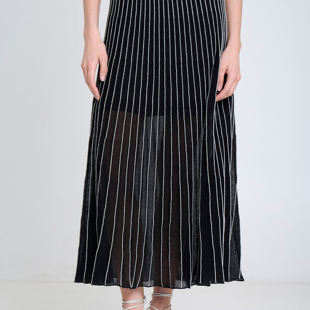 Person wearing a black pleated skirt with white stripes on a white background