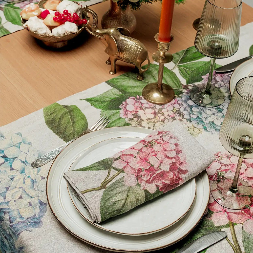 Elegant table setting with floral tablecloth, plates, and cutlery.