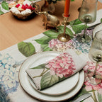 Elegant table setting with floral tablecloth, plates, and cutlery.