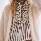 Person wearing a zebra-striped shirt under a beige cardigan with a blurred background