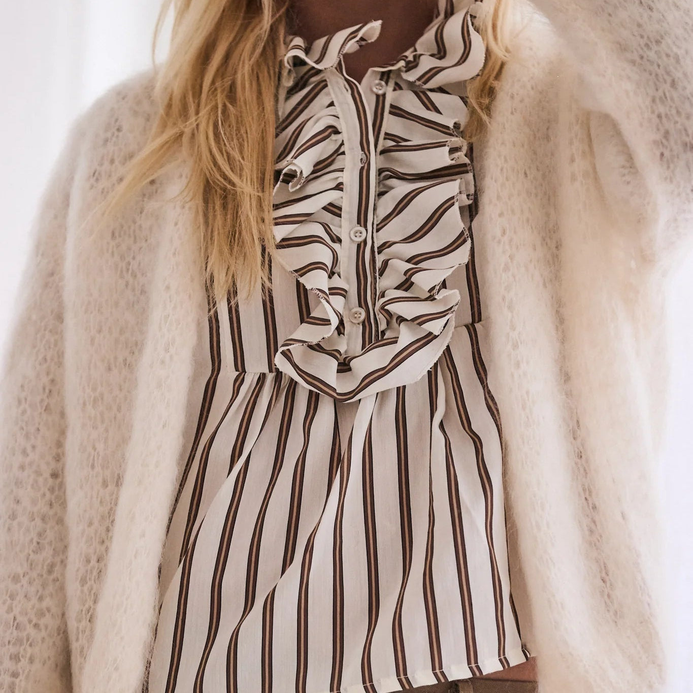 Person wearing a zebra-striped shirt under a beige cardigan with a blurred background