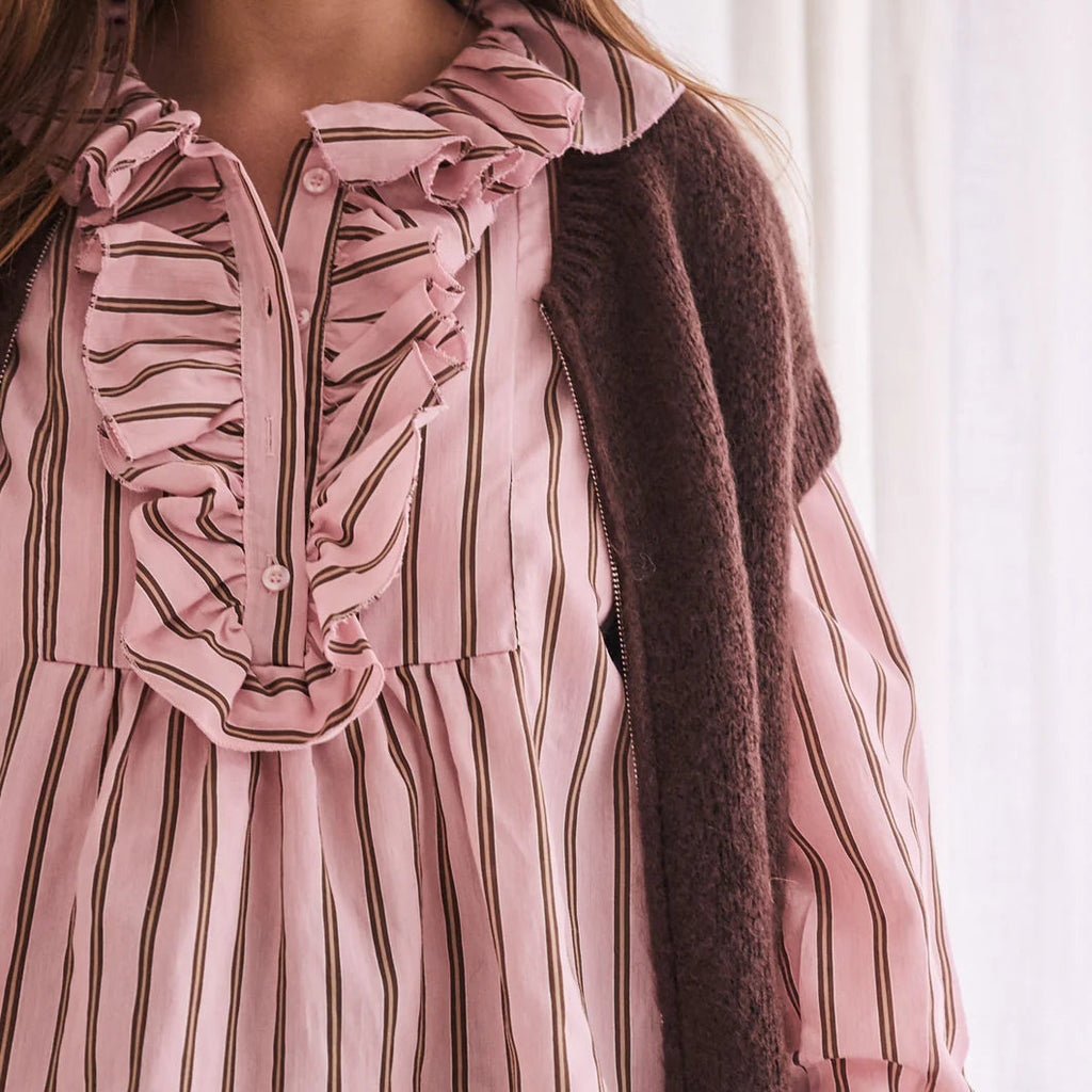 Close-up of a person wearing a pink striped blouse with a brown cardigan.