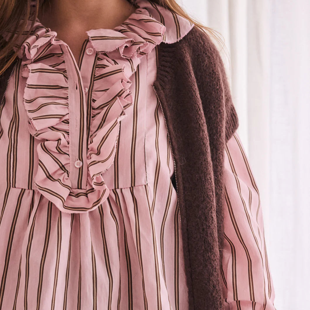 Close-up of a person wearing a pink striped blouse with a brown cardigan.