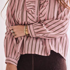 Person wearing a pink and white striped blouse with ruffled details.