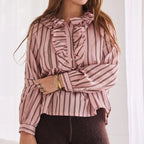 Woman wearing a pink and white striped blouse with a bow detail.