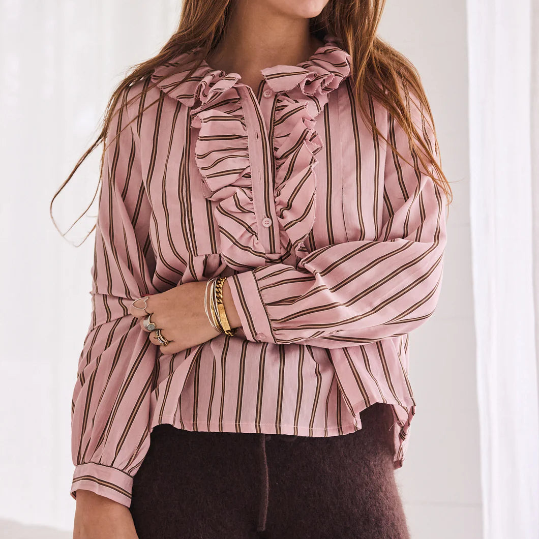 Woman wearing a pink and white striped blouse with a bow detail.