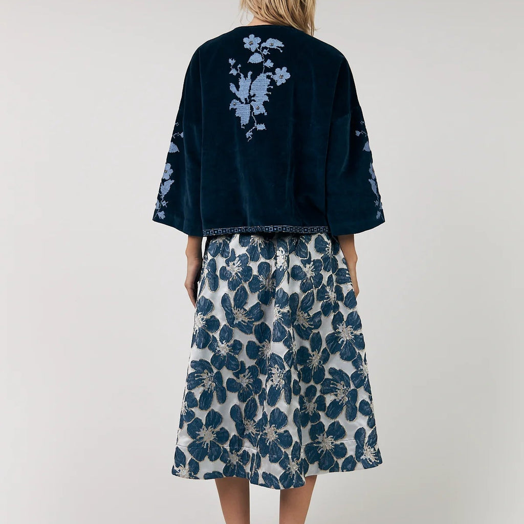 Woman wearing a navy kimono-style top with floral patterns and a matching skirt on a white background