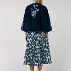 Woman wearing a navy kimono-style top with floral patterns and a matching skirt on a white background