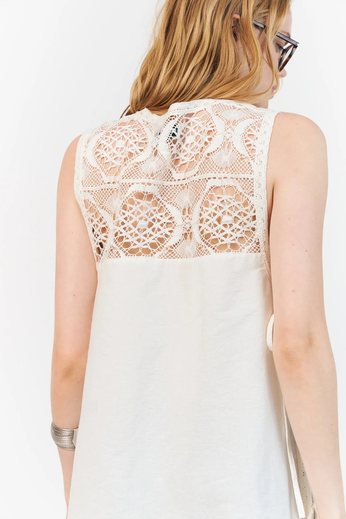 White sleeveless top with lace detailing on a plain background