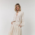 Woman wearing a beige outfit with a white background
