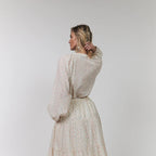Woman wearing a light-colored dress with long sleeves on a white background