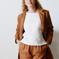 Woman wearing a brown coat and pants with a white top against a plain background