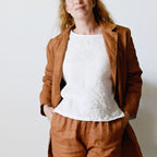 Woman wearing a brown coat and pants with a white top against a plain background