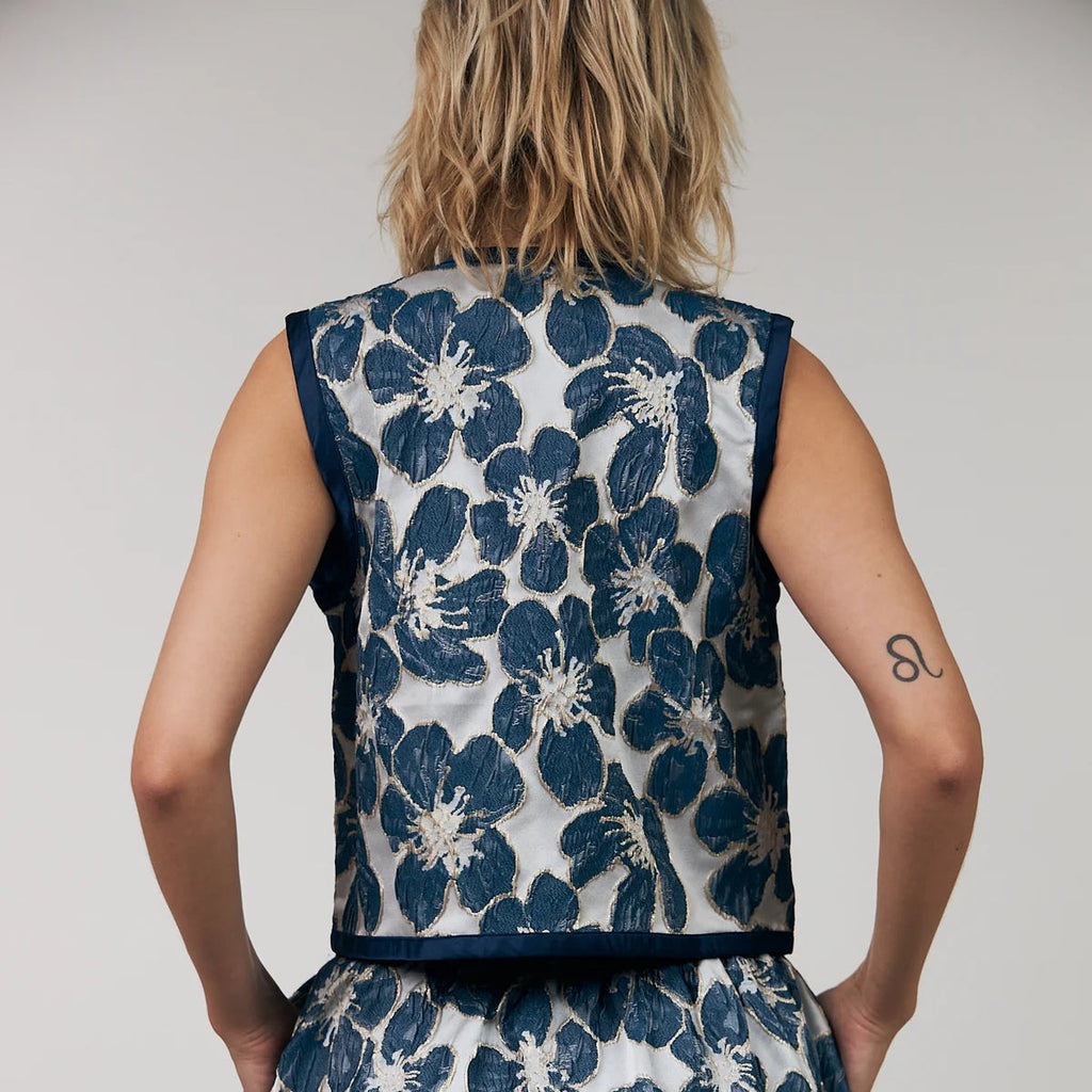 Woman wearing a blue floral dress against a plain background