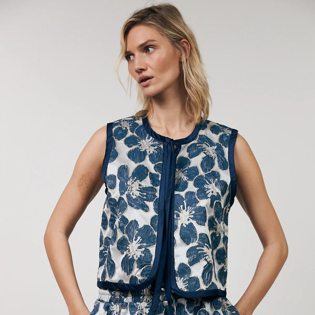 Woman wearing a blue floral dress against a plain background