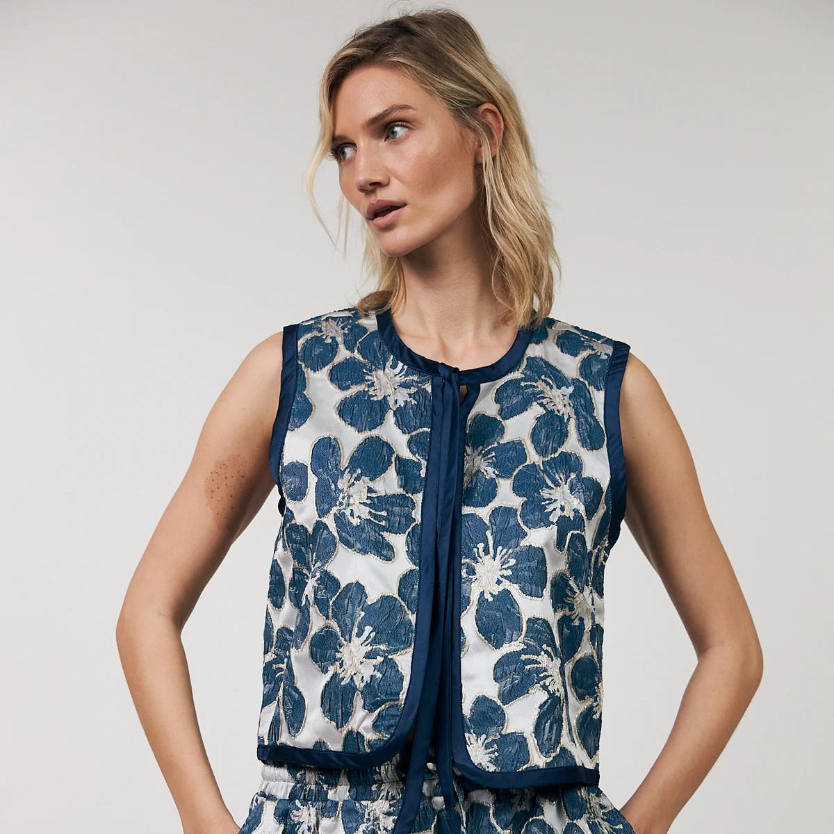 Woman wearing a blue floral dress against a plain background