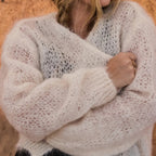 Woman wearing a light beige knitted sweater against a wooden background