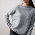 Woman wearing a gray sweater against a plain background