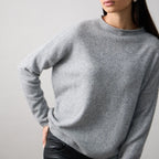 Woman wearing a gray sweater against a plain background