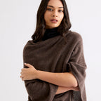 Woman wearing a brown poncho against a white background