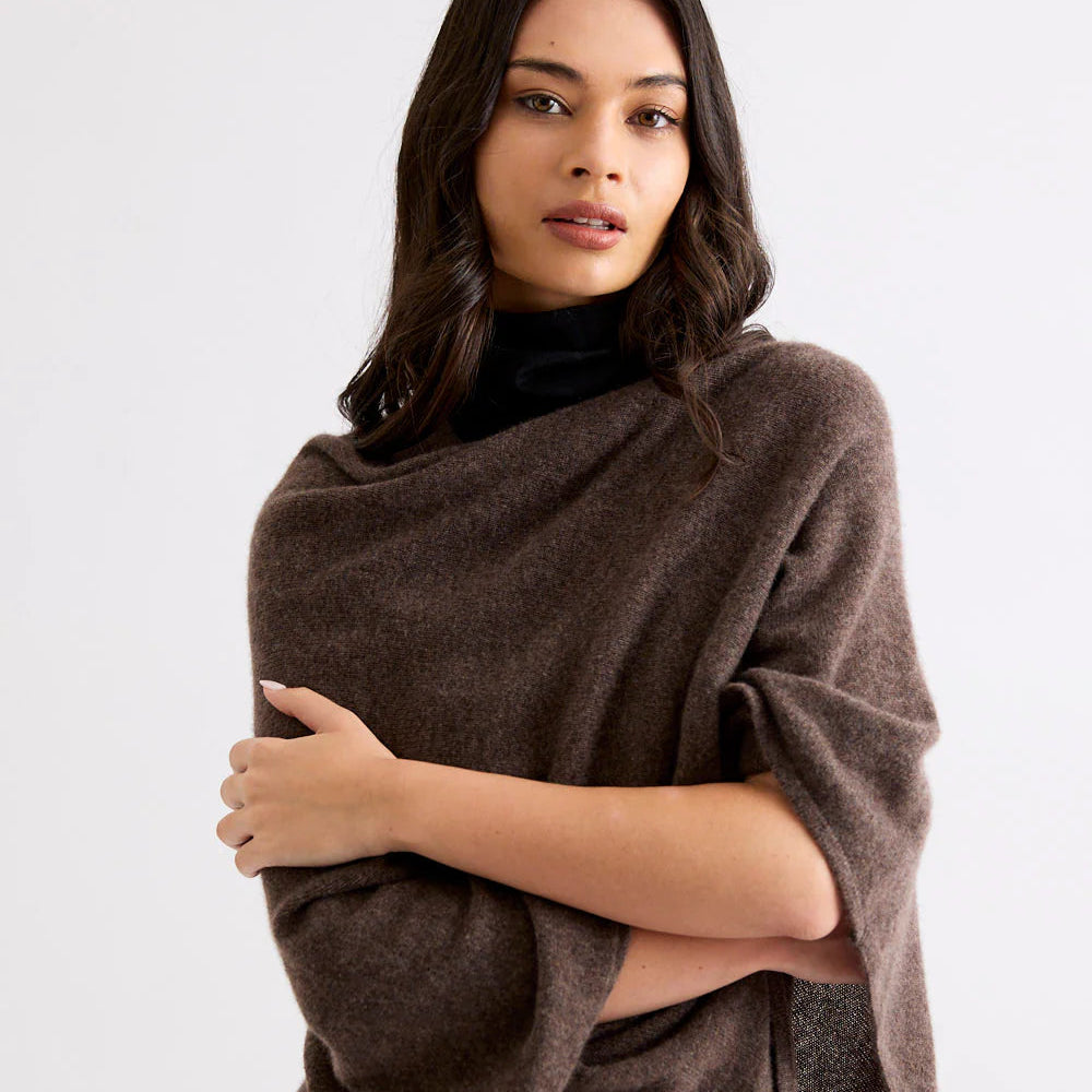 Woman wearing a brown poncho against a white background