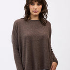 Woman wearing a brown sweater and light blue jeans on a white background