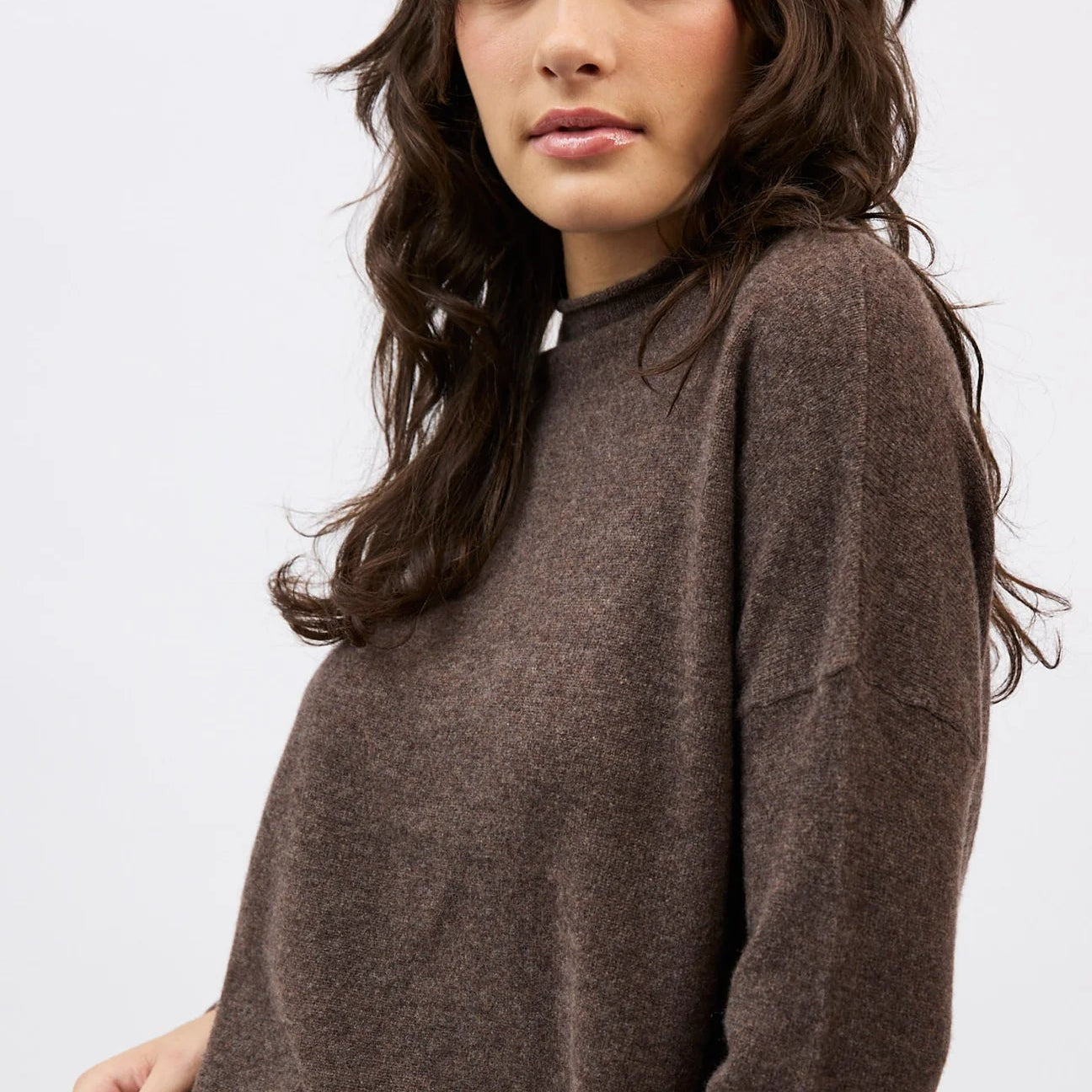 Woman wearing a brown sweater against a white background