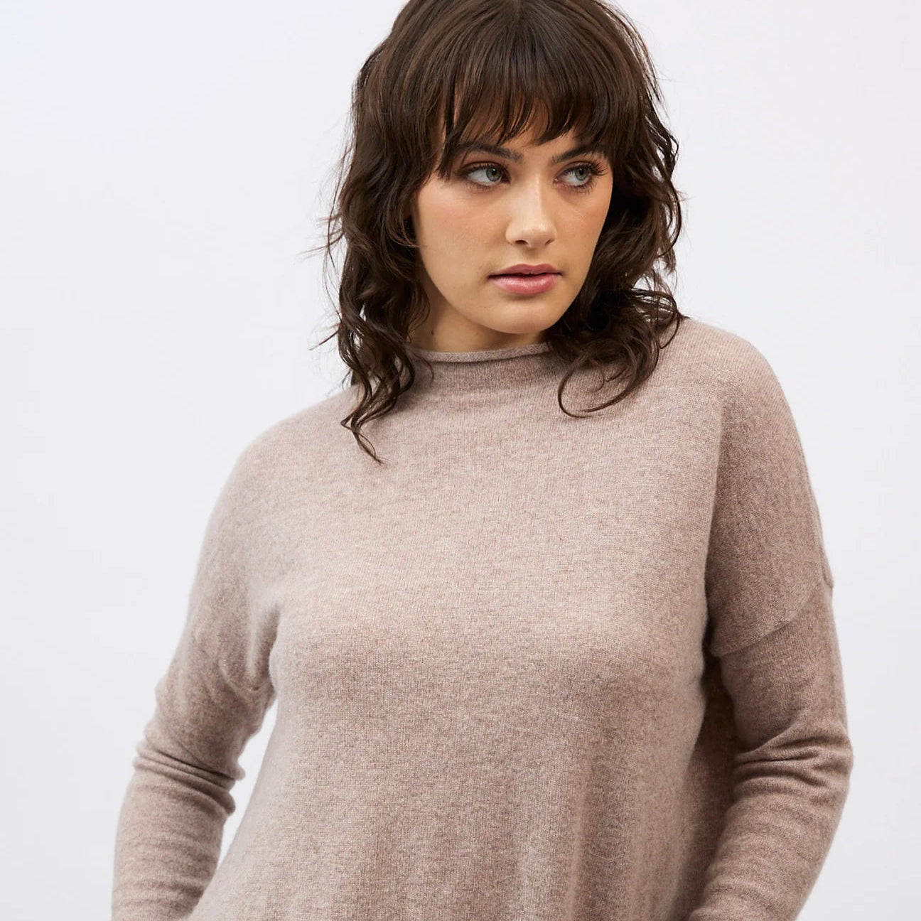 Woman wearing a beige sweater on a white background