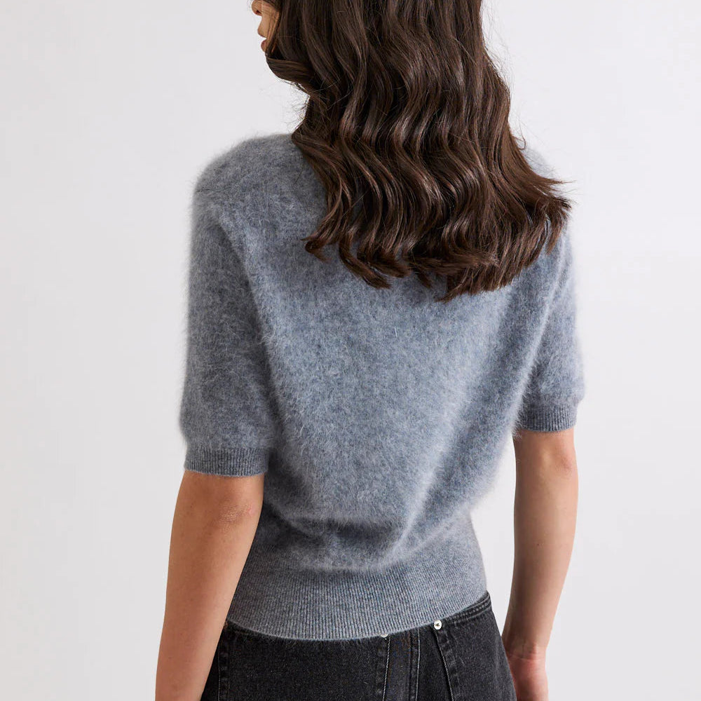 Person wearing a gray sweater and black pants on a white background