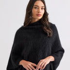 Woman wearing a black poncho against a white background