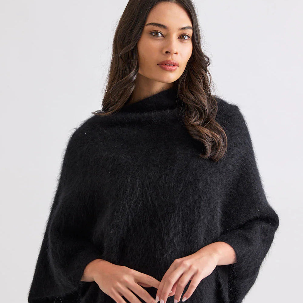 Woman wearing a black poncho against a white background