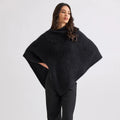 Woman wearing a black poncho and pants on a white background
