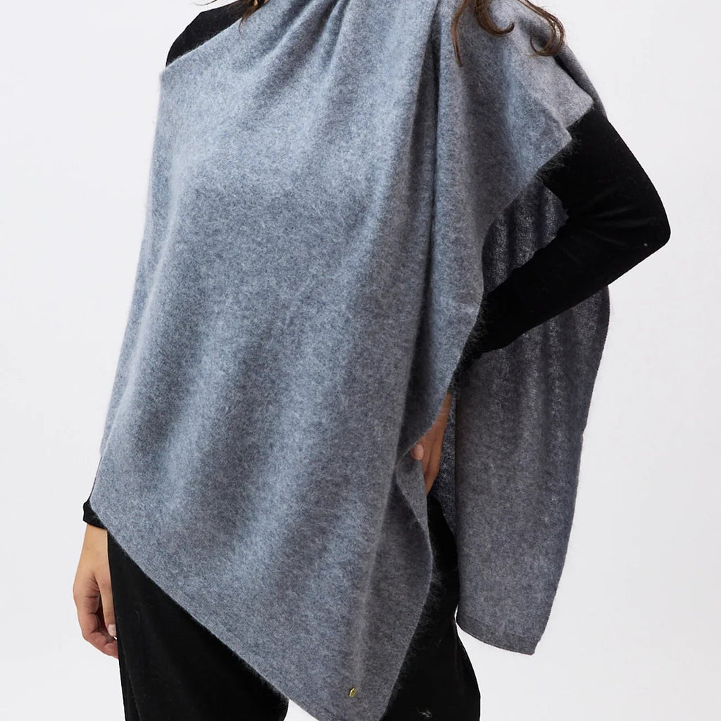 Woman wearing a gray poncho over a black top on a white background