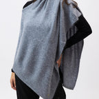 Woman wearing a gray poncho over a black top on a white background