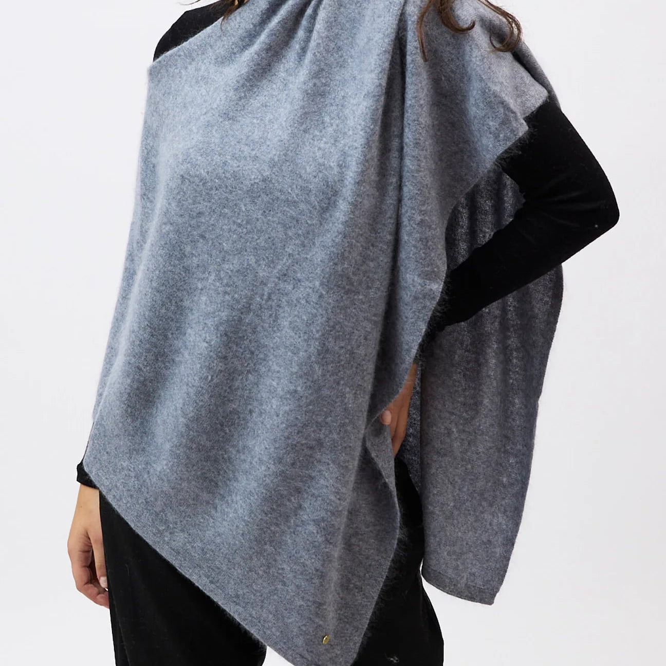 Woman wearing a gray poncho over a black top on a white background