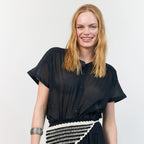Woman wearing a black outfit with a white and black patterned belt against a white background