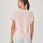 Person wearing a light pink top and light blue jeans on a plain background