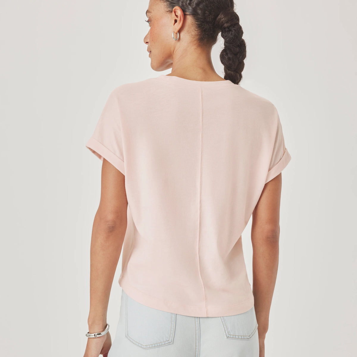 Person wearing a light pink top and light blue jeans on a plain background