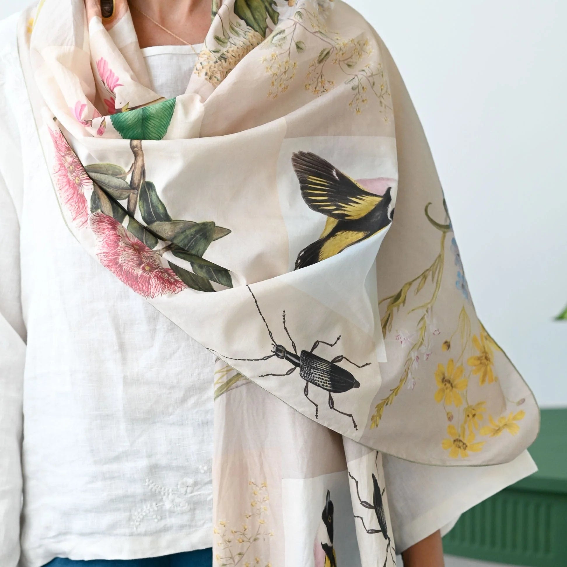 Person wearing a floral and insect patterned scarf with a white background