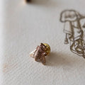 Small insect-shaped object on a textured surface with a faint illustration in the background
