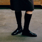Person wearing a black outfit with a beanie in front of wooden panels