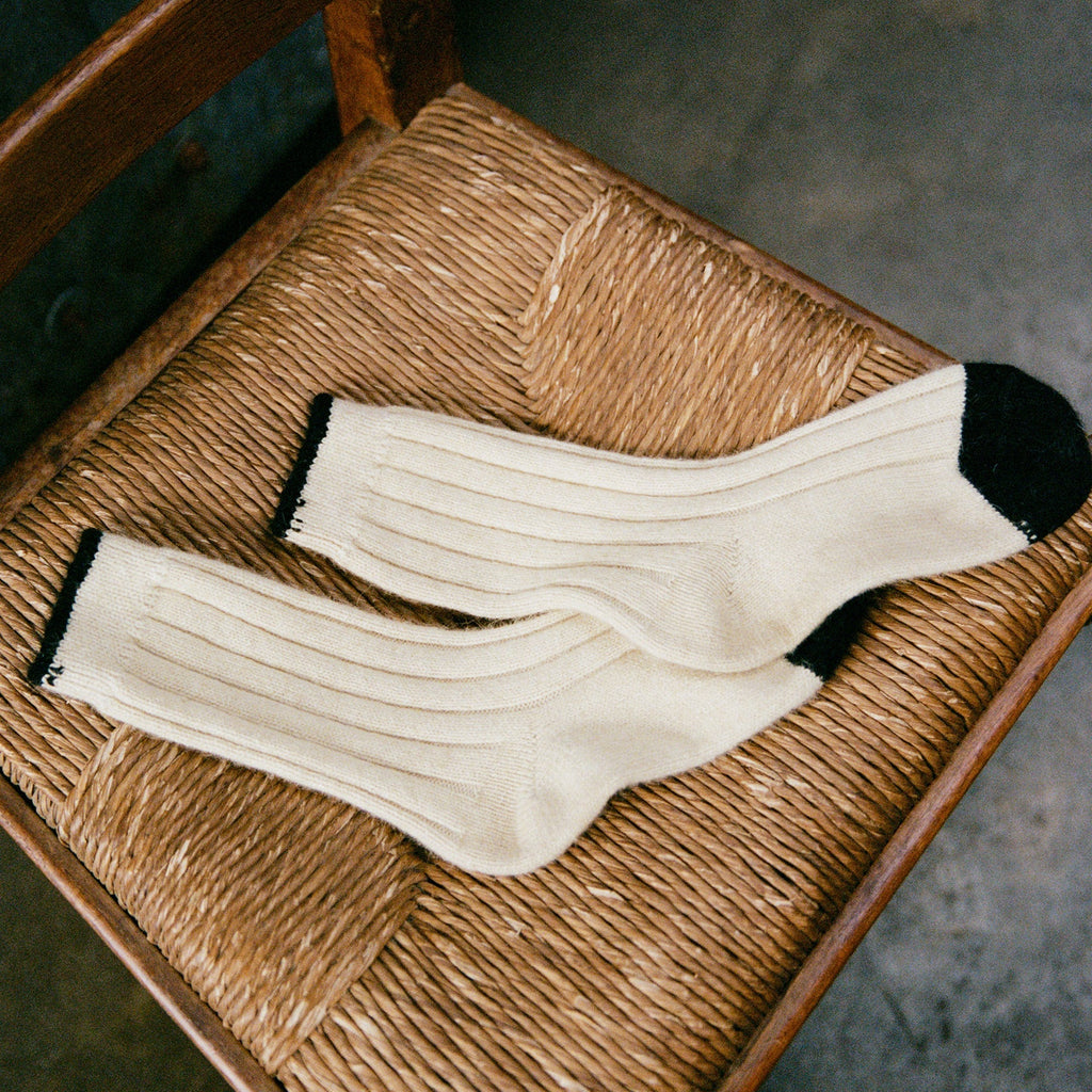 Pair of white socks with black accents on a woven chair.