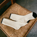 Pair of white socks with black accents on a woven chair.