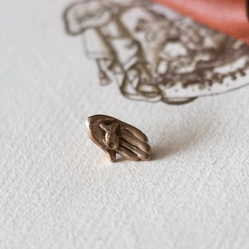 Small bronze figurine on a textured white surface with a red fabric background