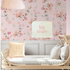 Children's room with floral wallpaper, 'big sister' pillows, and a crib.