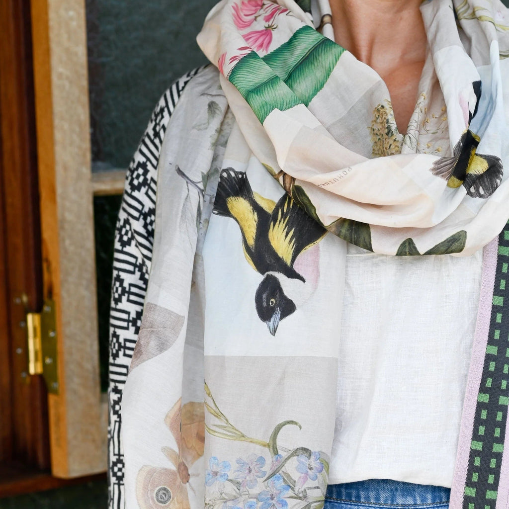 Woman wearing a floral and bird patterned scarf with a blurred background