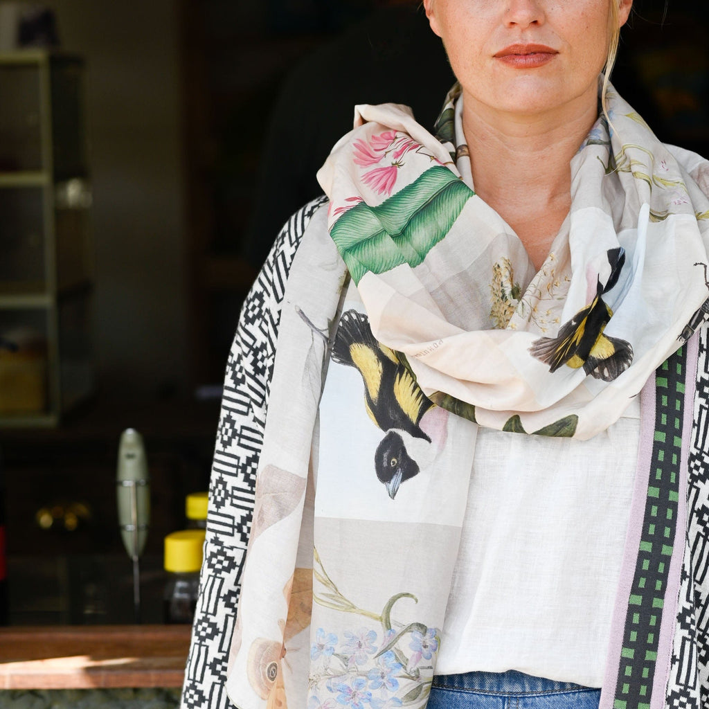 Woman wearing a floral and bird patterned scarf with a blurred background
