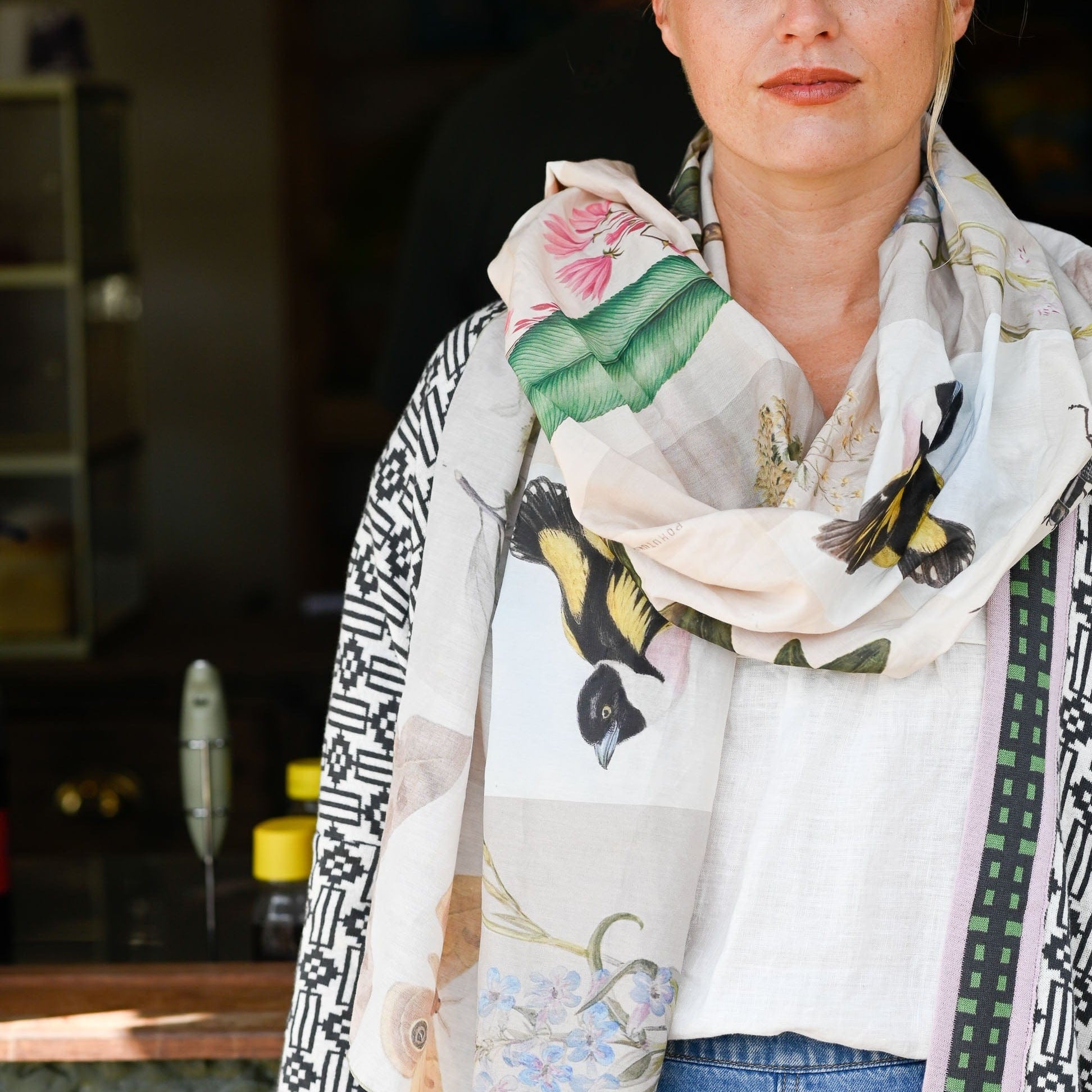 Woman wearing a floral and bird patterned scarf with a blurred background